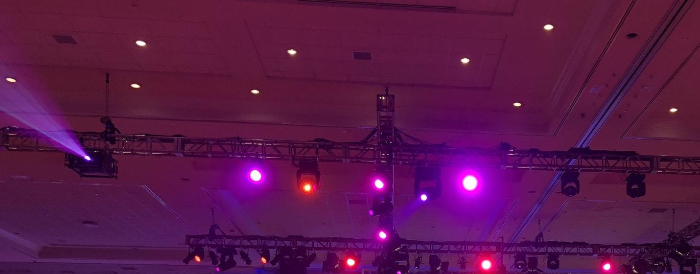 Moving heads and wash lights hung on box truss over a ballroom stage